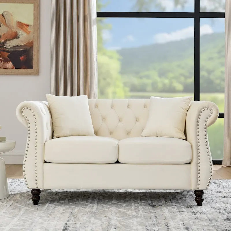 Causeuse en velours beige avec accoudoirs roulés et détails cloutés