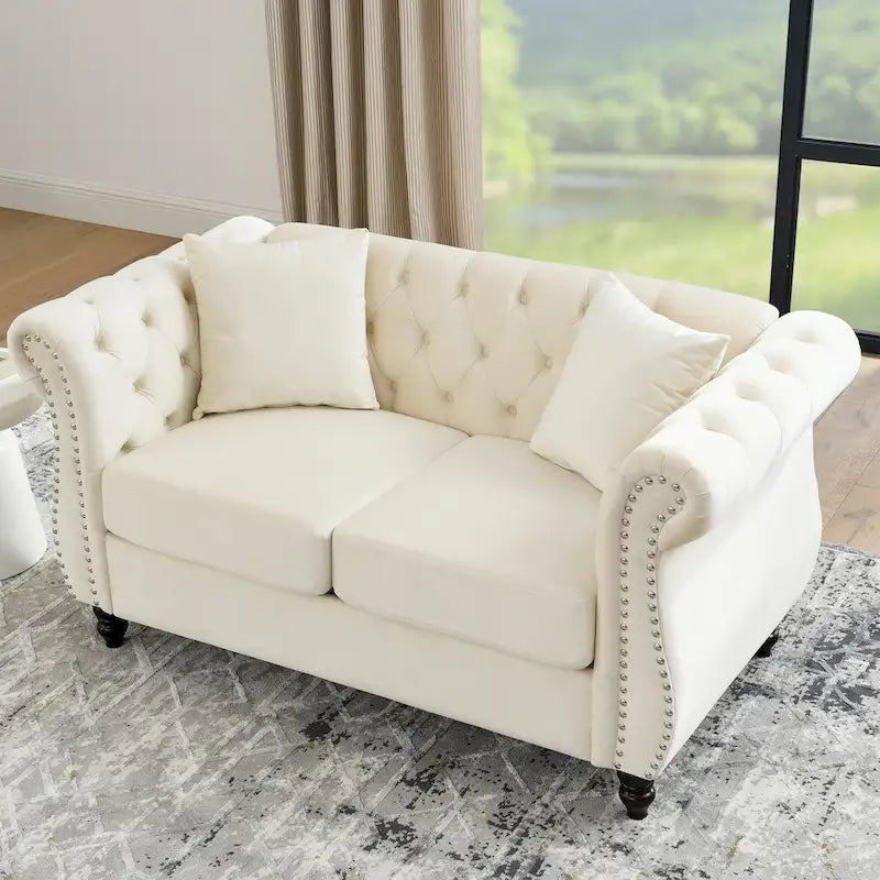 Causeuse en velours beige avec accoudoirs roulés et détails cloutés